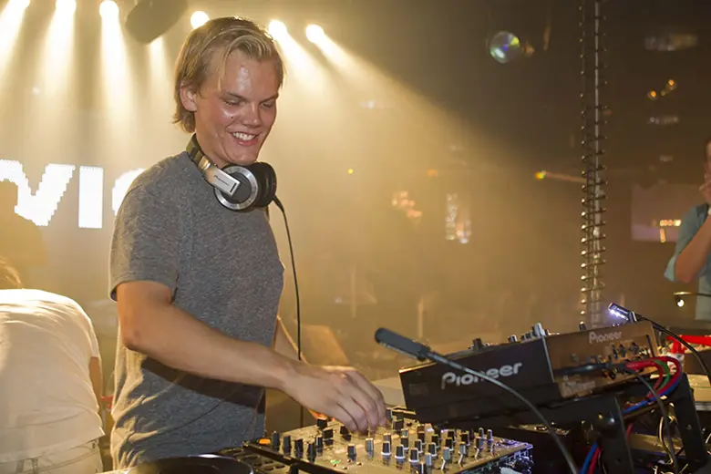 La imagen muestra a Avicii como DJ en el escenario.