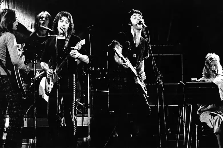 La imagen muestra a Paul McCartney en el escenario con su banda Wings.